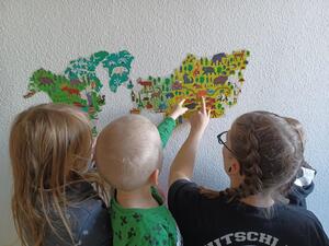 Die Kinder suchen andere Länder auf der Weltkarte.