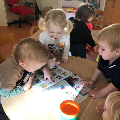 Die Kinder blttern in einem Katalog und sehen sich Spiele an.