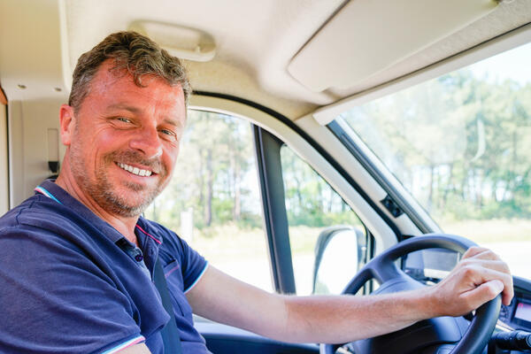Happy man van driver behind steering wheel of car driving concep