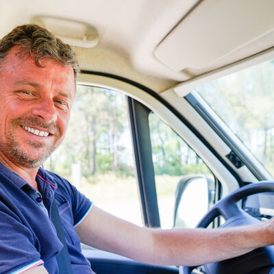 Happy man van driver behind steering wheel of car driving concep