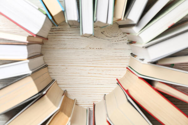 Heart made of books on white wooden rustic background, top view