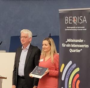 Projektkoordinatorin Kerstin Olesch erh&auml;lt F&ouml;rdertafel von Staatssekret&auml;r Wolfgang Beck.