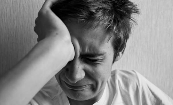 Teen boy cries and holds his hand behind his head
