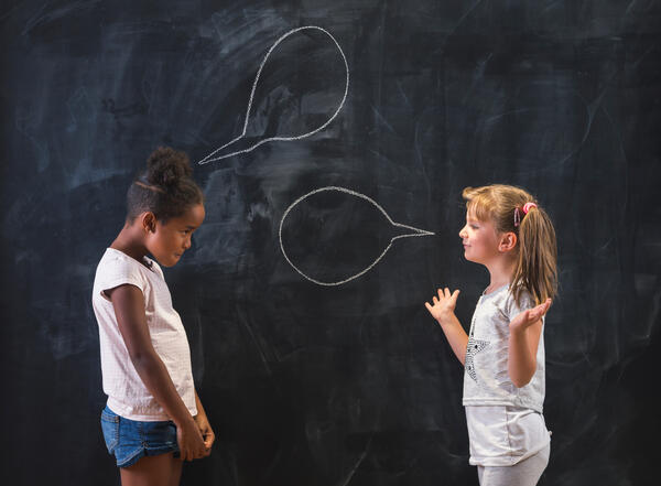 Schoolgirls having a discussion and debate in front of a chalkboard