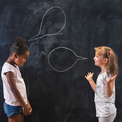Schoolgirls having a discussion and debate in front of a chalkboard