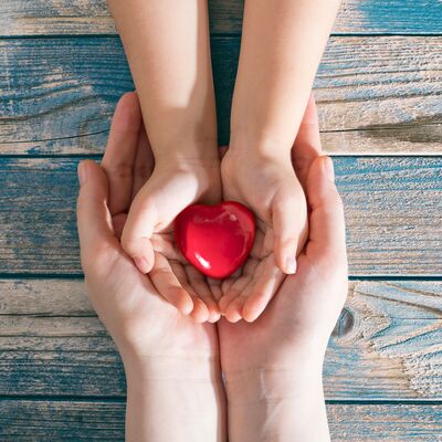 mother and daughter hands are holding red heart. Heart health co