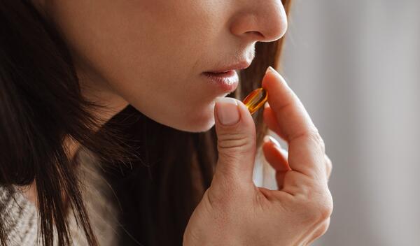 The close-up shot of a woman holding a pill to her mouth and holding a glass of water