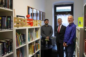 Tafelkoordinator Andreas Knospe (l.) und AWO-Gesch&auml;ftsf&uuml;hrer Kai-Gerrit B&auml;dje (r.) zeigen Helge Albrecht von der Harzsparkasse die neue Tafel-Bibliothek Eselsohr