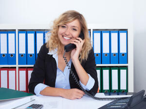 Frau mit blonden Locken im B&uuml;ro lacht am Telefon