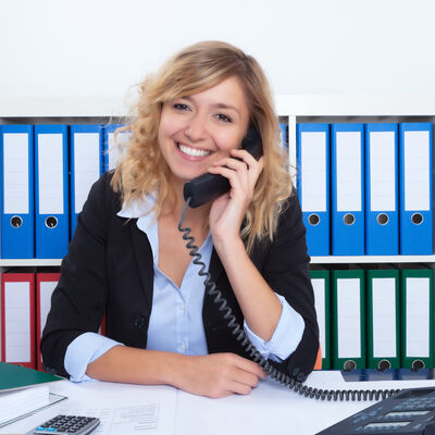 Frau mit blonden Locken im Büro lacht am Telefon