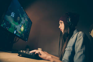 Low below angle view side profile photo of cyber sports woman concentrated on bringing victory to her team pressing buttons on keyboard
