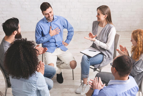 Happy people clapping at support group meeting