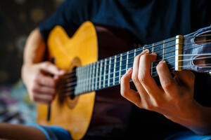 young musician playing acoustic guitar, live music background