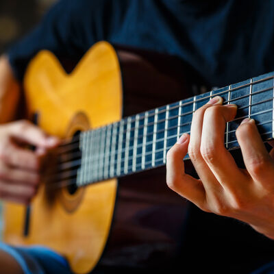 young musician playing acoustic guitar, live music background